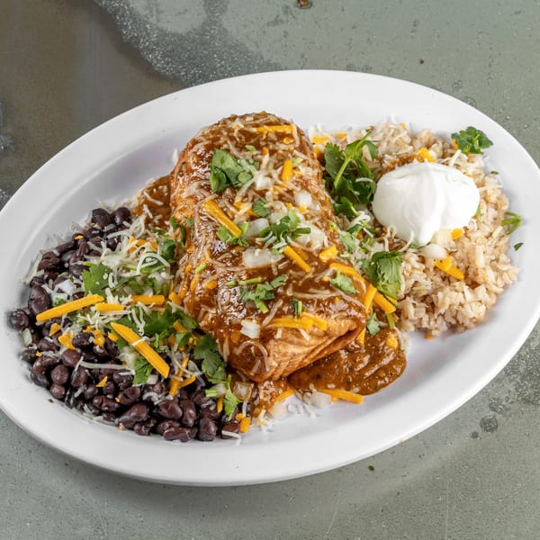A Raging Burrito smothered in sauce and cheese, served with black beans, rice, and sour cream.