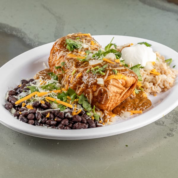 A Raging Burrito smothered in sauce and cheese, served with black beans, rice, and sour cream.