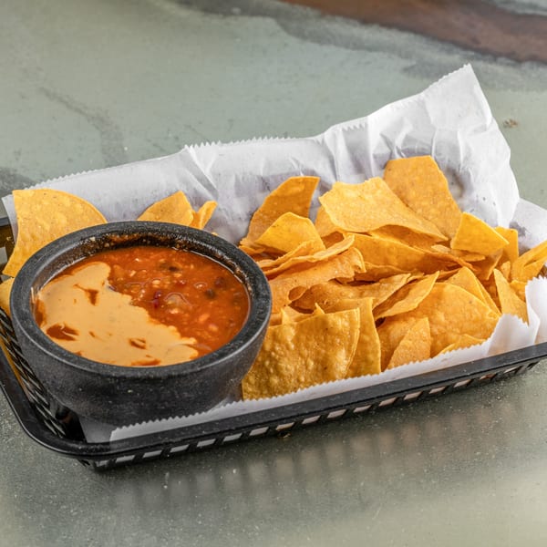 A basket of Raging Burrito's tortilla chips with a side of queso and salsa.