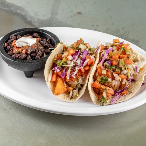 Two Raging Burrito tacos with fried fish, cabbage, and salsa, served with a side of black beans.