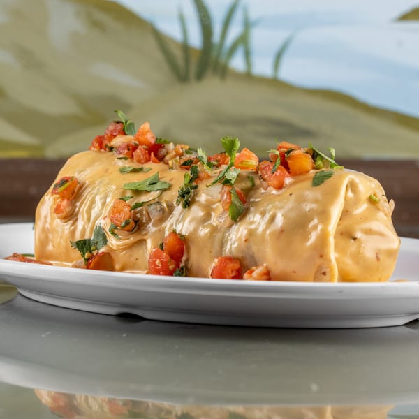 A Raging Burrito smothered in creamy cheese sauce, topped with diced tomatoes and cilantro.