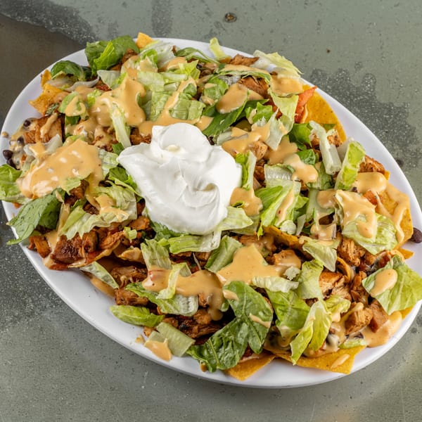 Raging Burrito's chicken nachos with lettuce, creamy sauce, and a dollop of sour cream.