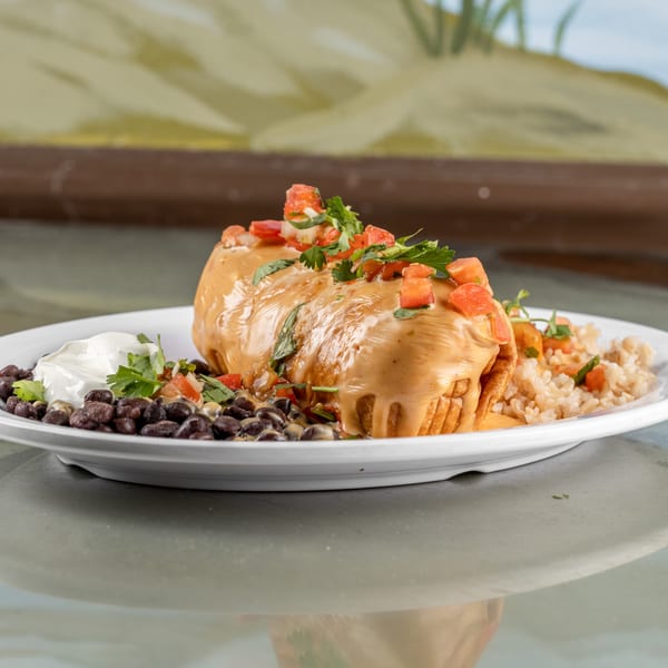 A Raging Burrito smothered in cheese sauce, topped with pico de gallo, served with black beans and rice.