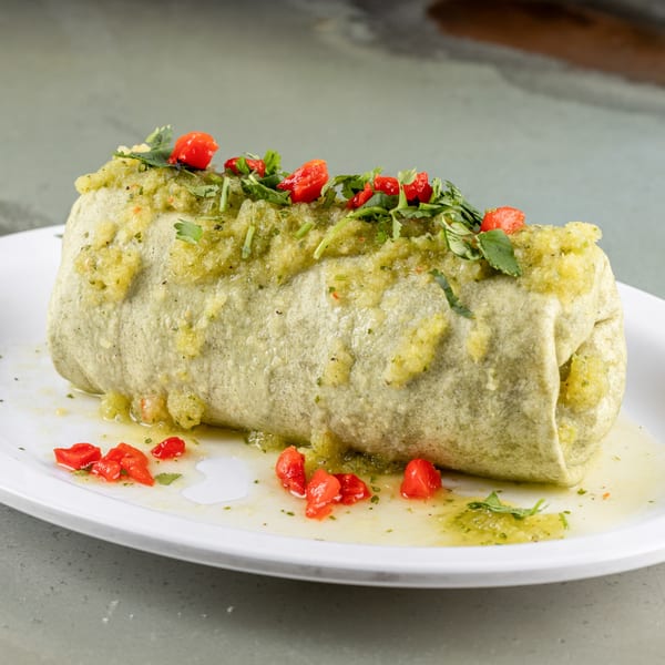 A Raging Burrito, generously covered in green salsa, cilantro, and diced red peppers.