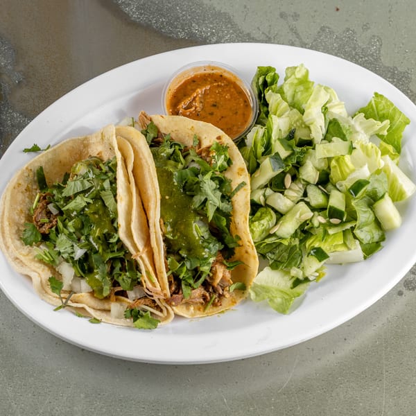 Two Raging Burrito tacos with green sauce, cilantro, and onions, served with a side salad and salsa.
