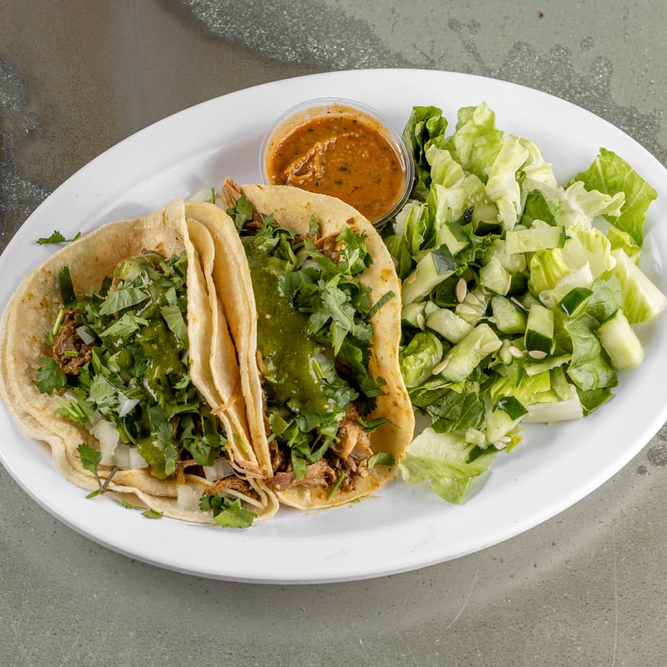Two Raging Burrito tacos with green sauce, cilantro, and onions, served with a side salad and salsa.