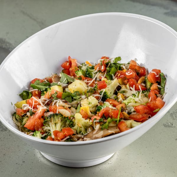 Close-up of a Raging Burrito bowl filled with fresh tomatoes, broccoli, and shredded cheese.